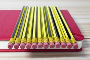 Wooden 2b pencils lying on red note book on wooden table. Copy space. photo