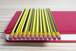 Wooden 2b pencils lying on red note book on wooden table. Copy space. photo
