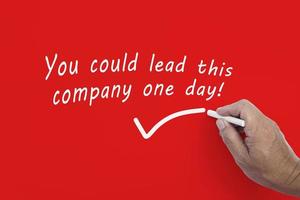 Hand writes in white chalk pencil the word YOU COULD LEAD THIS COMPANY ONE DAY. photo