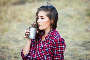 hermosa mujer bebe té al aire libre. mujer hipster relajándose en la naturaleza foto