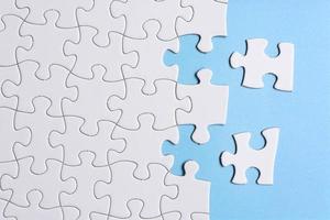 White jigsaw puzzle with some missing pieces on blue background. Copy space. photo