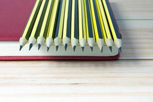 Wooden 2b pencils lying on red note book on wooden table. Copy space. photo
