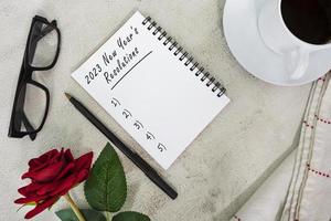 2023 New Year's Resolutions written on notebook on white marble table. photo