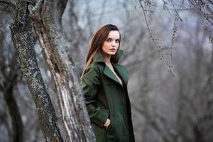 imagen de una mujer hermosa joven que usa una chaqueta para la lluvia cuando hace frío. pensadora chica europea en la naturaleza de primavera. foto