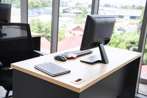 Modern office interior design with table computer monitor notebook and big glass window around the room without people photo