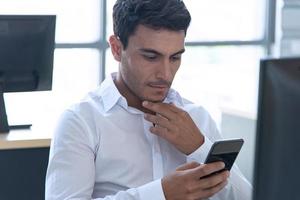 Young confident executive, manager seriously working on computer and using smartphone in modern and creative office. Working in social distancing situation. photo