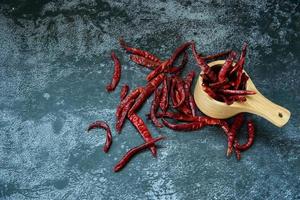 pimiento picante rojo seco en la cuchara de madera sobre fondo de textura gris, el chile es ingrediente de la comida tailandesa foto