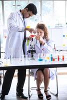 Young woman and man reserchers, scientists, technicians or students conducting research or experiment by using scientific, medical equipment or device in chemistry laboratory photo