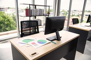 Modern office interior design with table computer monitor notebook and big glass window around the room without people photo