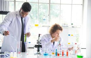 Young woman and man reserchers, scientists, technicians or students conducting research or experiment by using scientific, medical equipment or device in chemistry laboratory photo