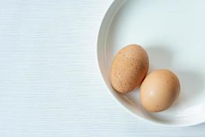 Raw fresh chicken eggs or boiled eggs  or boiled eggs on whith plate isolated white gray line texture background photo