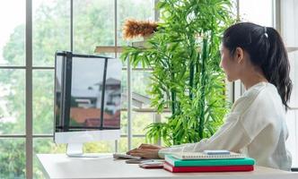 Work from home and online learning concept. Pretty young women working on computer look at the screen in the living room or co-working space. Student study online training course. photo