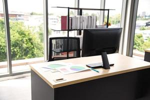 Modern office interior design with table computer monitor notebook and big glass window around the room without people photo