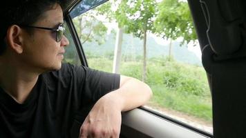 Tourist man sitting in car looking outside to view a nature scene at local street travel video