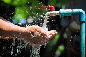 Water concept in everyday life. Hands supporting the water flowing from the faucet. water splashing from the tap photo