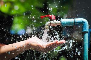 concepto de agua en la vida cotidiana. manos sosteniendo el agua que fluye del grifo. agua salpicando del grifo foto