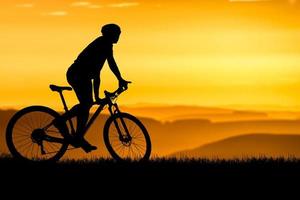 siluetas de bicicletas de montaña y ciclistas por la noche felizmente. concepto de viaje y fitness. silueta de ciclistas recorriendo el concepto de cicloturismo vespertino foto