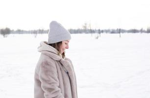 Young girl in beige clothes, fur coat made of artificial fur walks in winter photo