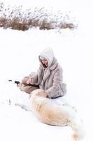 Young beautiful woman and her golden retriever dog having fun in winter. photo