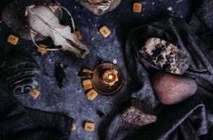 Old dog skull, burning candle, wooden runes and stones on the witch table. photo