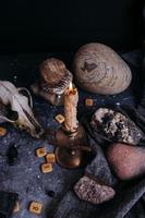 Old dog skull, burning candle, wooden runes and stones on the witch table. photo