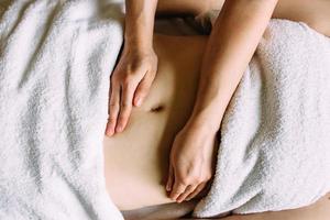 The masseur gives a massage to the female belly at the spa. The concept of cosmetic procedures. photo