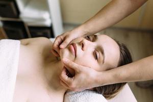 Masseur doing massage on a woman's face at the spa. The concept of cosmetic procedures. photo