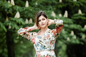 Woman's portrait with a hair moving in the wind.  portrait of young beautiful Russian brunette girl at summer green park. European white woman in dress. photo