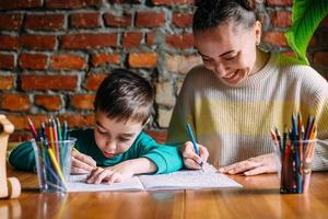 Child and adult are drawing a coloring book. photo