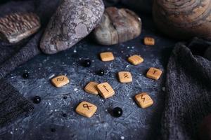 Fortune telling on wooden runes among stones. Gloomy and mysterious witch table. photo