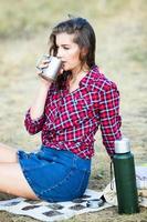 Beautiful woman drinks tea outdoors. Hipster woman relaxing in nature photo