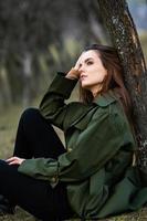 Image of young beautiful woman wearing rain jacket in cold weather. Thinker european girl in spring nature. photo