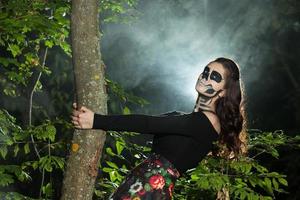 Halloween Vampire Woman portrait over scary night background. Vampire makeup Fashion Art design. Model girl in Halloween costume and make up. photo