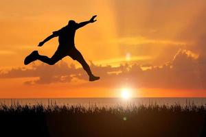 The silhouette of a man is jumping forward. The concept of clawing through hurdles photo