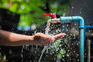 Water concept in everyday life. Hands supporting the water flowing from the faucet. water splashing from the tap photo