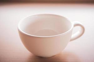 An old white teacup was placed on the table in the morning with light and shadow. photo