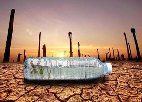 concepto de sequía por escasez de agua debido al calentamiento global. botellas de agua colocadas en áreas de sequía y suelo roto foto
