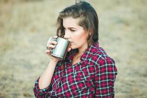 Beautiful woman drinks tea outdoors. Hipster woman relaxing in nature photo