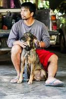 Asian man sits with a dog in his home photo