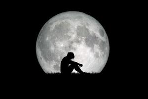 Desperate and lonely man in the background of the moon at night. Desperate, heartbreaking, and lonely concepts photo