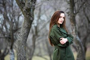 Image of young beautiful woman wearing rain jacket in cold weather. Thinker european girl in spring nature. photo