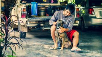 hombre asiático se sienta con un perro en su casa foto