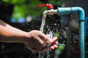 Water concept in everyday life. Hands supporting the water flowing from the faucet. water splashing from the tap photo