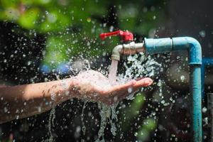 Water concept in everyday life. Hands supporting the water flowing from the faucet. water splashing from the tap photo