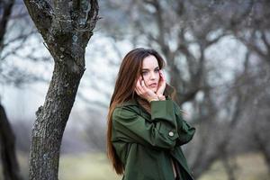 imagen de una mujer hermosa joven que usa una chaqueta para la lluvia cuando hace frío. pensadora chica europea en la naturaleza de primavera. foto