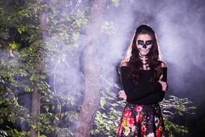 Halloween Vampire Woman portrait over scary night background. Vampire makeup Fashion Art design. Model girl in Halloween costume and make up. photo