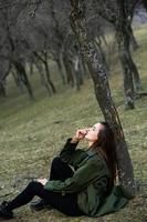 Image of young beautiful woman wearing rain jacket in cold weather. Thinker european girl in spring nature. photo