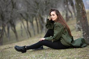 Image of young beautiful woman wearing rain jacket in cold weather. Thinker european girl in spring nature. photo