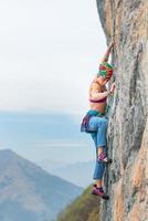 Young woman stairs a wall during a rock course photo