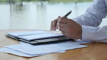 Business man working with document in public park with water pond background video